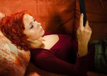 Young woman on a couch interacting with tablet pc or e-reader