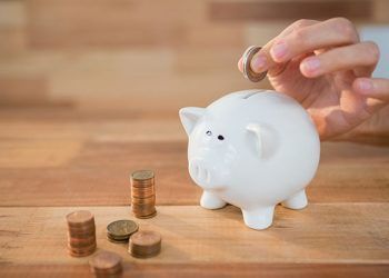 Close-up of hand inserting coin in piggy bank