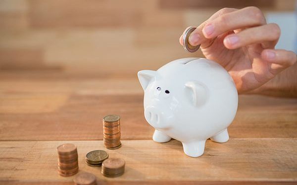 Close-up of hand inserting coin in piggy bank
