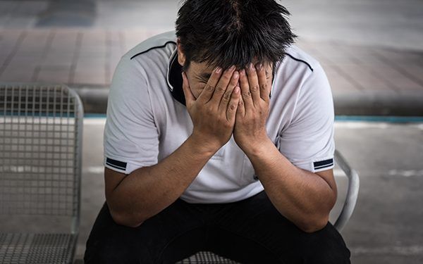 Man fired from job sitting hold the head with hand and worried stressed face expression outside office