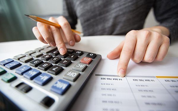 Closeup of accountant counting on calculator and working with table