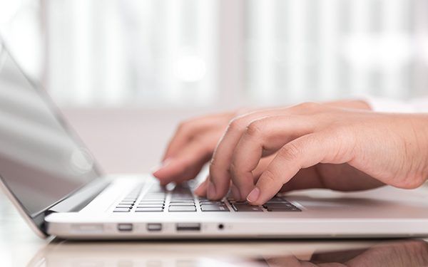 Closeup of business woman hand typing on laptop keyboard