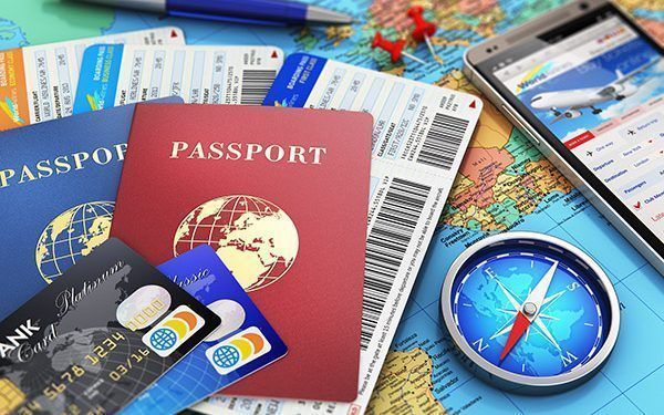Creative abstract business travel and tourism concept: air tickets or boarding pass, passports, touchscreen smartphone with online airline tickets booking or reservation internet application, magnetic compass, credit cards and pen on world geographic map atlas with selective focus effect