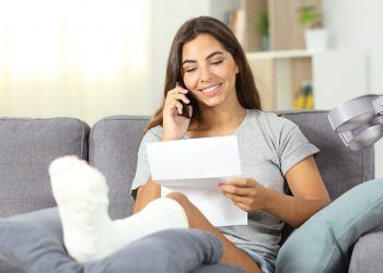 Disabled woman on the phone reading a letter sitting on a couch in the living room at home