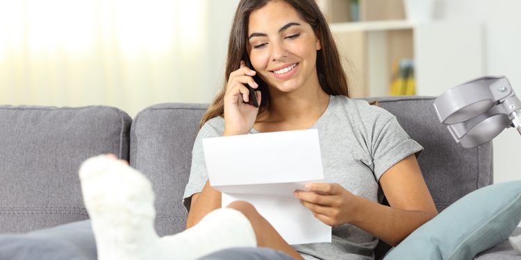 Disabled woman on the phone reading a letter sitting on a couch in the living room at home