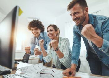 Young successful business people celebrating success while working on a new project in the casual office.
