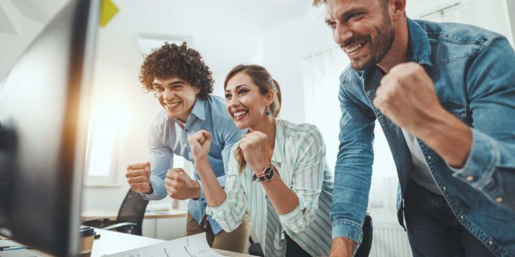 Young successful business people celebrating success while working on a new project in the casual office.