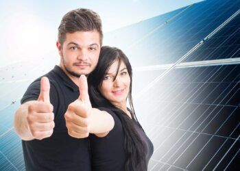 Happy couple showing like on solar power photovoltaic panel background  as green energy solution concept