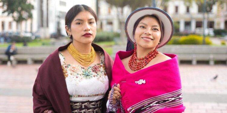 Two women showcasing vibrant indigenous fashion, adorned in traditional attire with colorful textiles and intricate jewelry, reflecting cultural pride and heritage in a lively urban setting