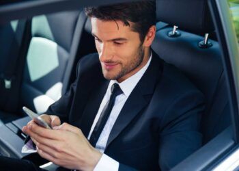 Handsome businessman using smartphone in car