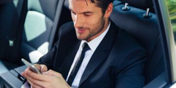Handsome businessman using smartphone in car
