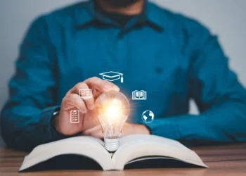 Hombre mirando un foco de luz inspirado en ideas de educación al abrir el libro